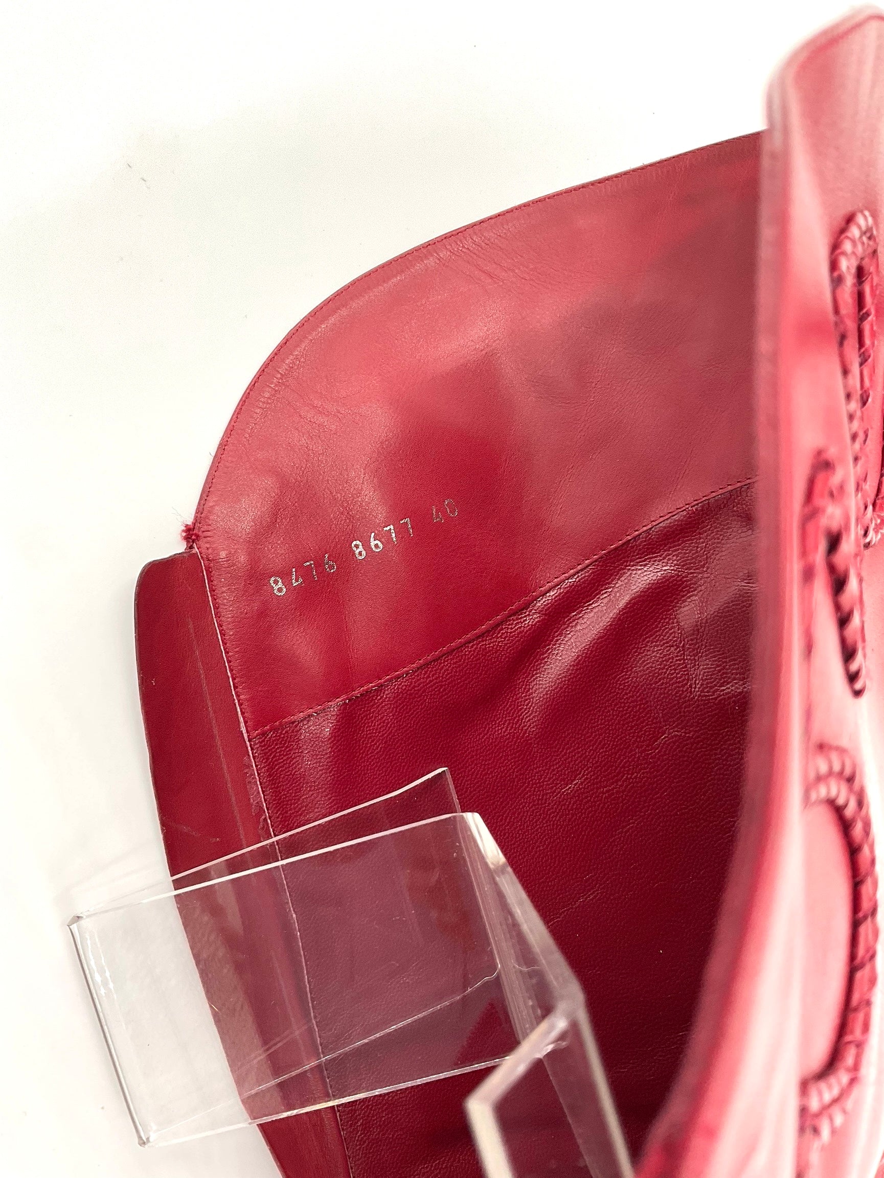 Close-up of a red boot inside with serial number and shoe size. a clear protective cover on a white background