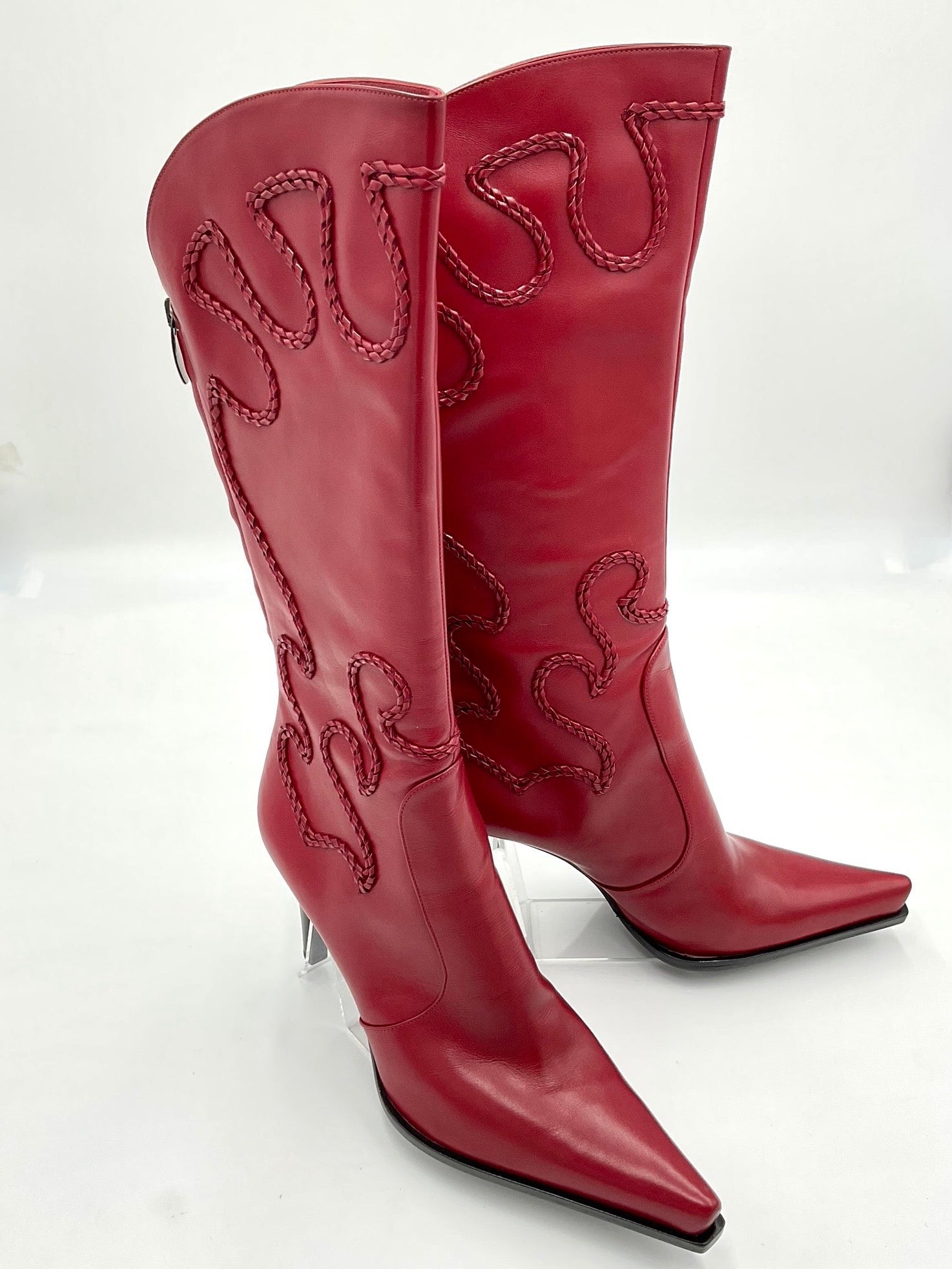 Red cowboy boots with intricate stitching on a white background