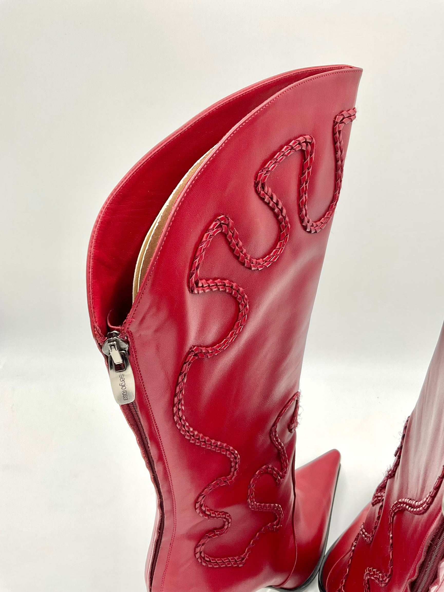 Red leather boot with intricate stitching on a white background