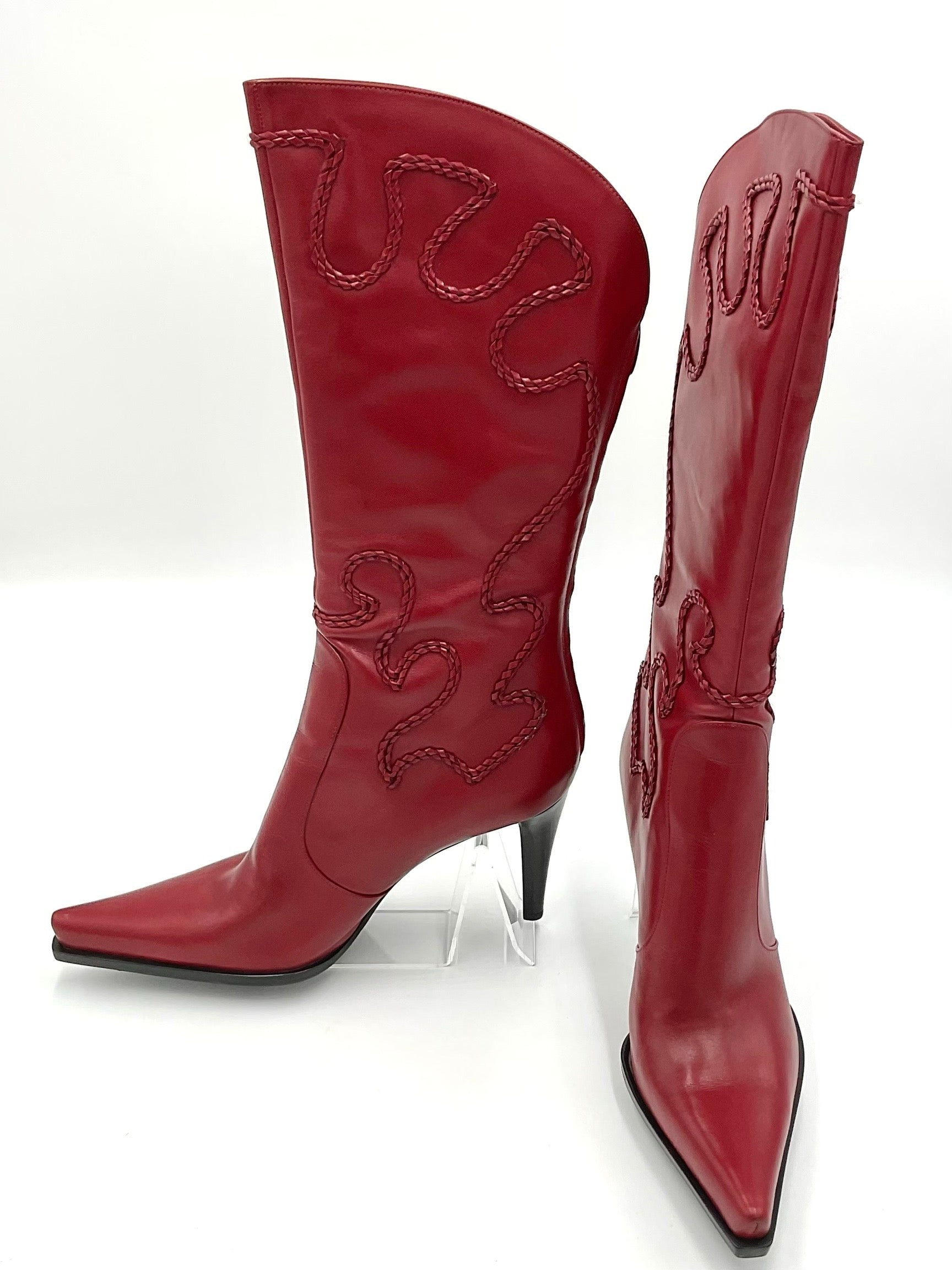 Red cowboy boots with intricate designs on a white background