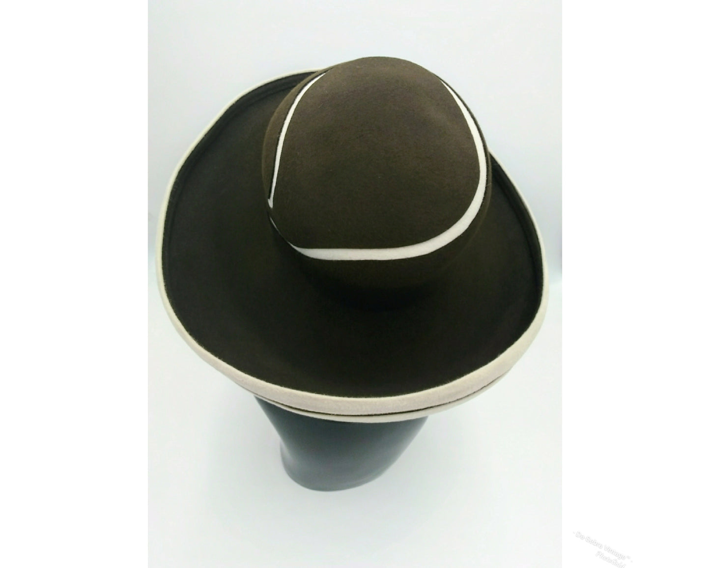 Black mannequin head with a cream and Chocolate brown striped hat on cream with a Chocolate brown background