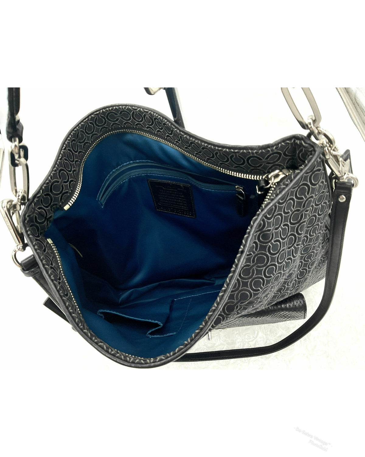 Black Coach  jacquard shoulder bag with a bright blue interior lining, shown open against a white background.