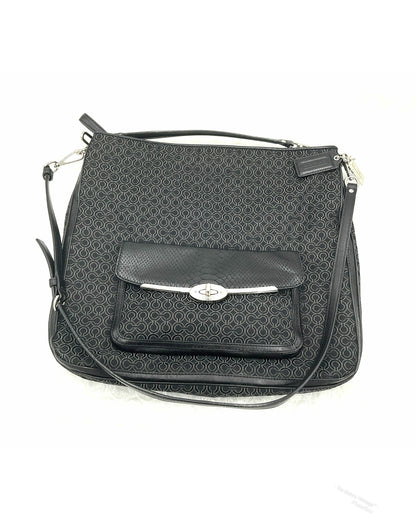 A black jacquard Coach crossbody handbag with a repeating monogram pattern, a front flap pocket with a silver-tone turn-lock closure, and a top handle, shown on a white background.