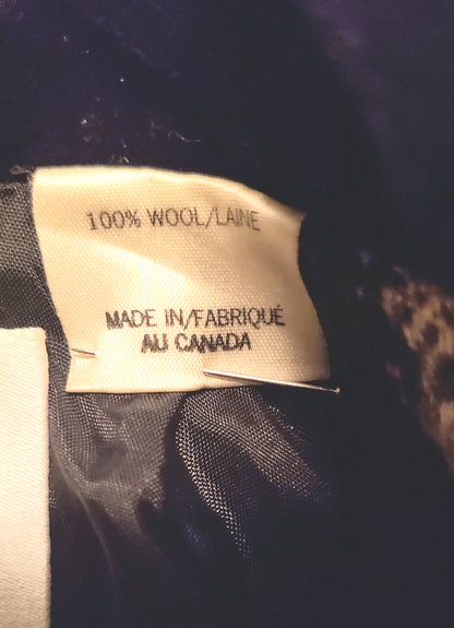 Close-up of a sewn-in fabric label reading '100% WOOL/LAIN' and 'MADE IN/FABRIQUÉ AU CANADA' attached to dark  black fabric lining.