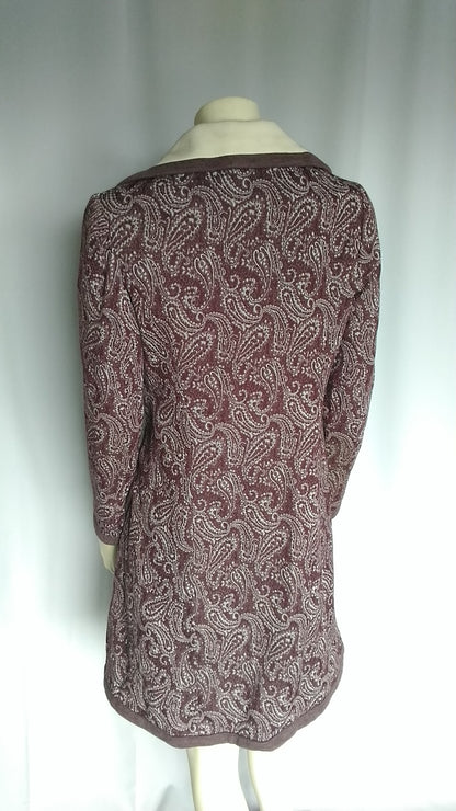 A long-sleeve tunic top with a brown and white paisley pattern, displayed on a mannequin against a white curtain background.