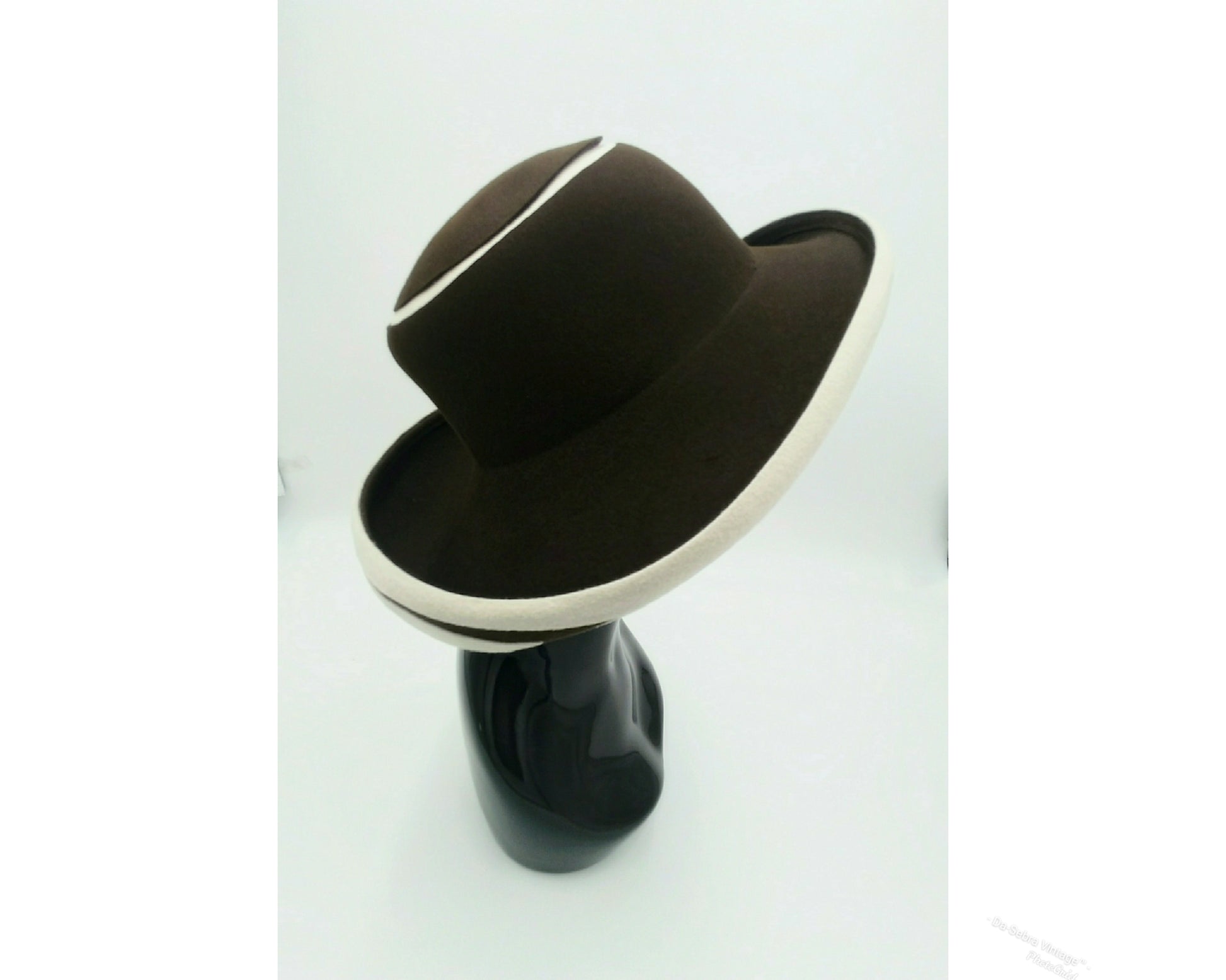 Black mannequin head with a cream and Chocolate brown striped hat on  cream with a Chocolate brown background