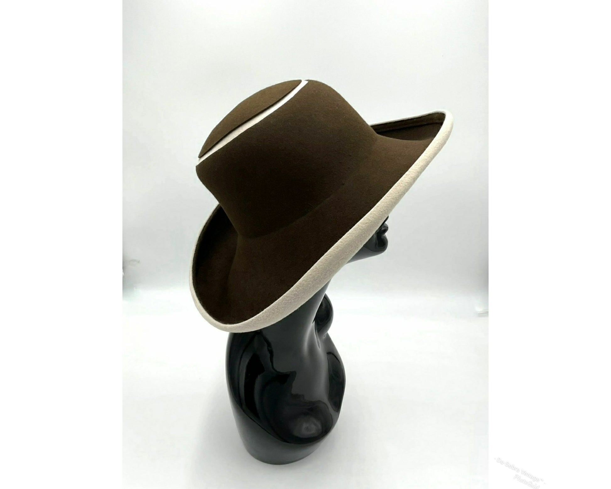 Black mannequin head with a cream and Chocolate brown striped hat on  cream with a Chocolate brown background