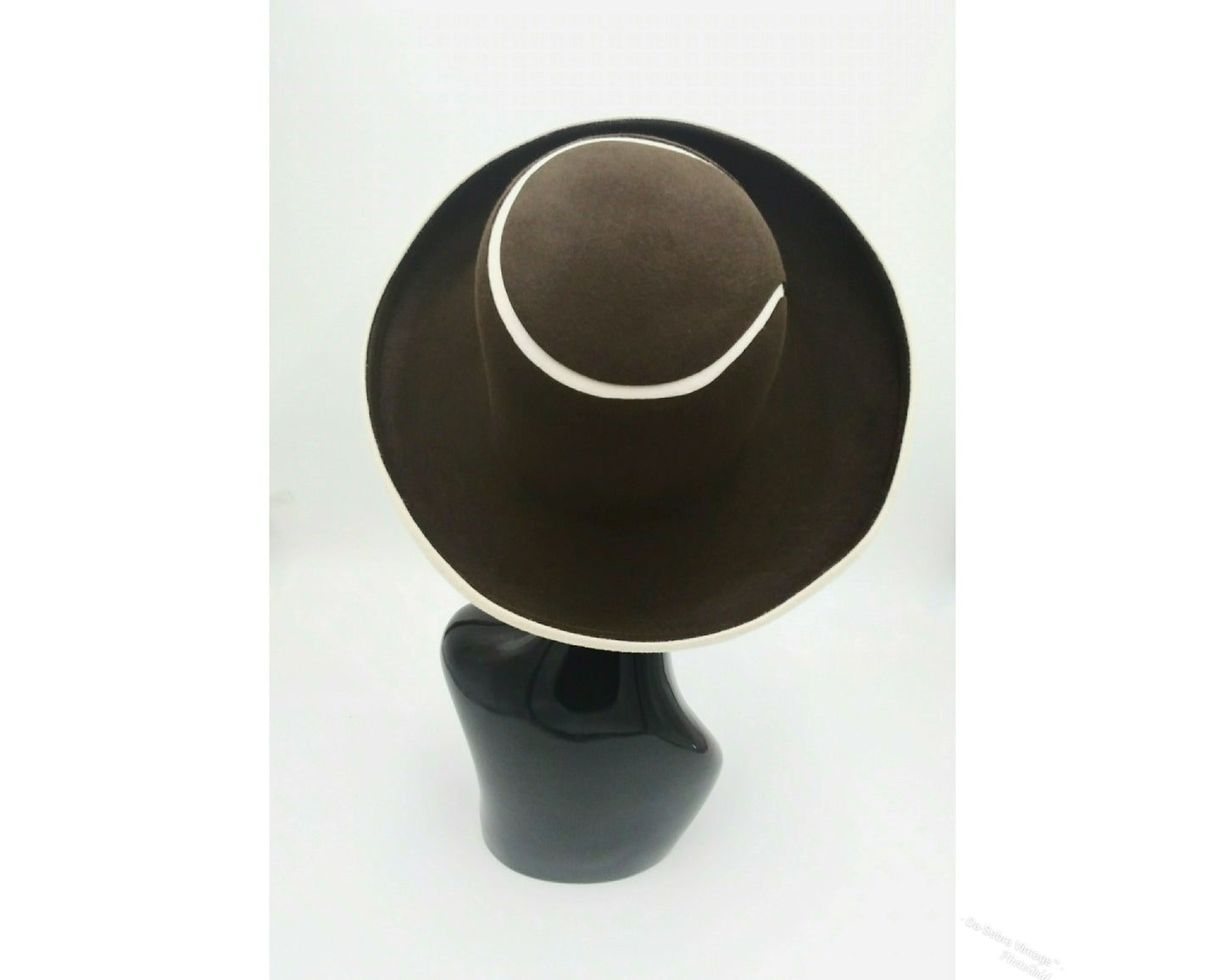 Black mannequin head with a cream and Chocolate brown striped hat on  cream with a Chocolate brown background
