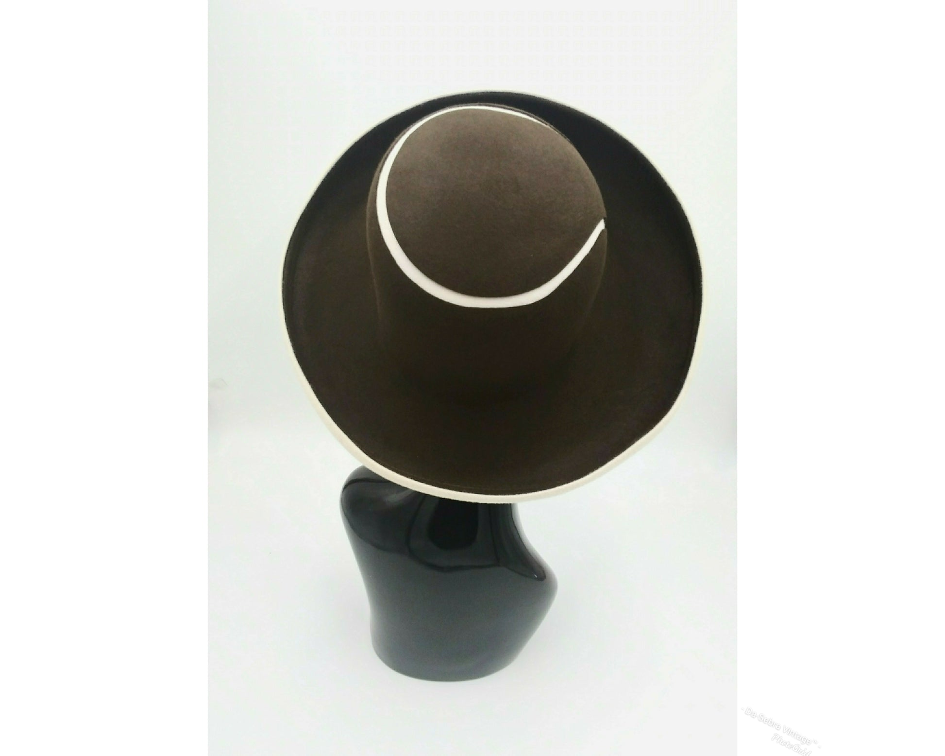Black mannequin head with a cream and Chocolate brown striped hat on  cream with a Chocolate brown background