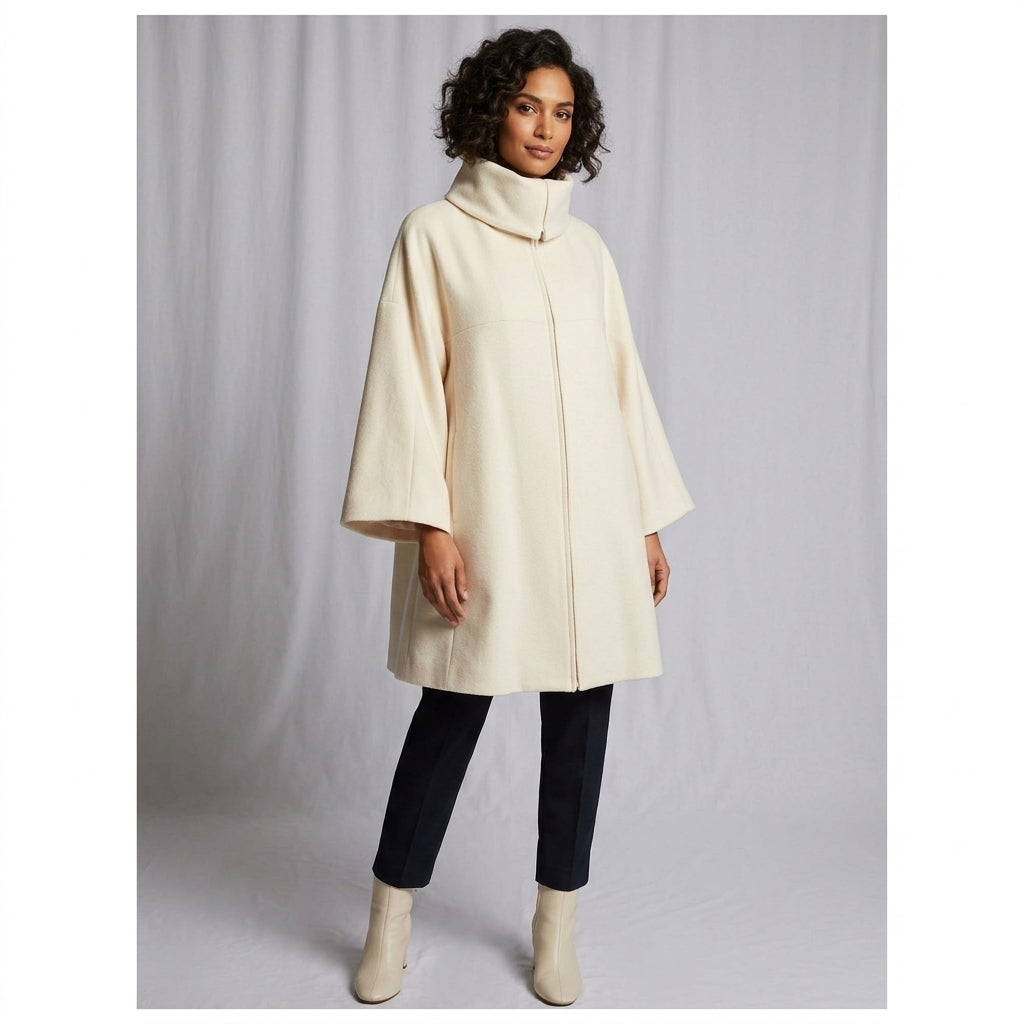 Model  wearing Cream Swing Coat with black leggings and cream boots with a gray back ground.