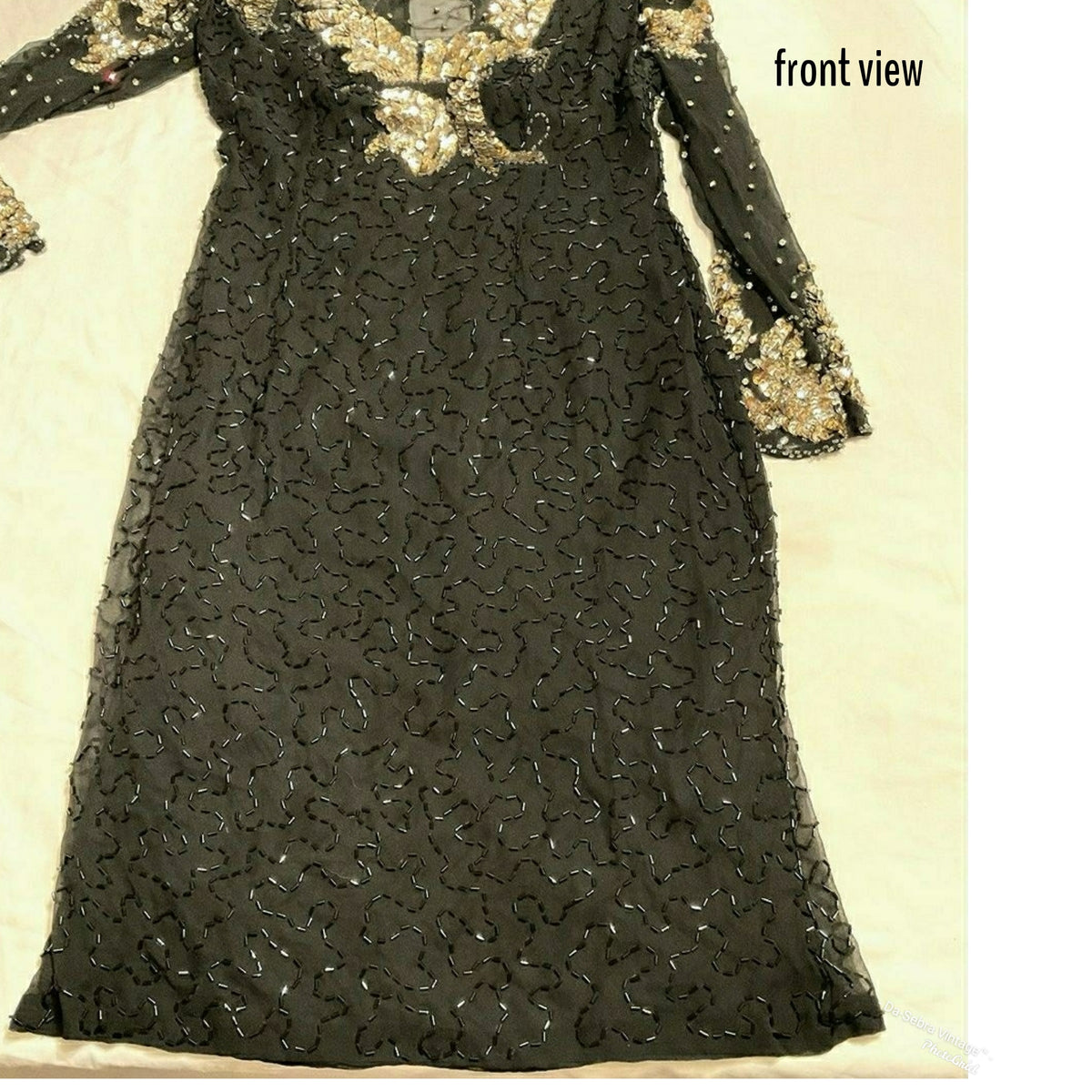 A black long-sleeved dress with intricate gold and silver sequin embroidery. With black bugle beads, laid flat on a light beige background. The image includes a text overlay in the top right corner that reads 'front view' closeup  view of the bugle beads on dress