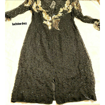 Close up to view beading on Black long-sleeve dress with gold sequin embroidery and beaded detailing, shown from the back on a light fabric background.