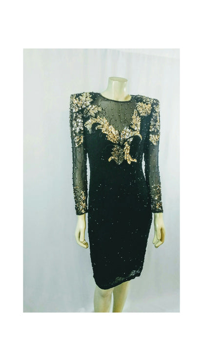 A black long-sleeve evening dress with gold and silver sequin and bead floral embroidery on the bodice and sleeves, displayed on a mannequin against a light gray background.
