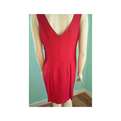 A bright red sleeveless V-neck dress displayed on a mannequin, featuring a front zipper closure and side pockets, set against a mint green wall and wooden floor.