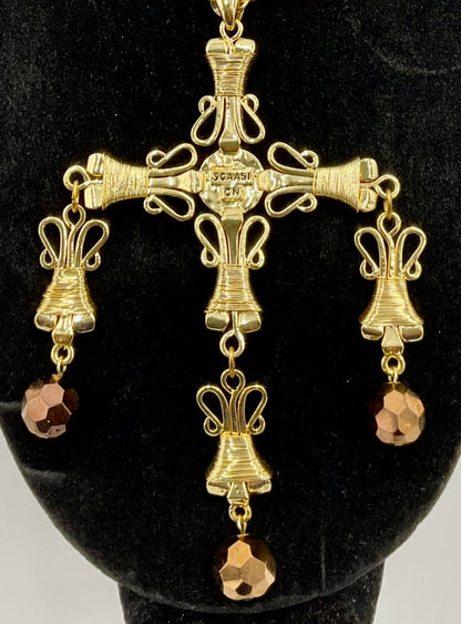 The back of Gold-toned ornate cross pendant with three dangling bell-shaped charms and faceted brown crystal drops, displaying the signature if SCAASI on a black mannequin bust.