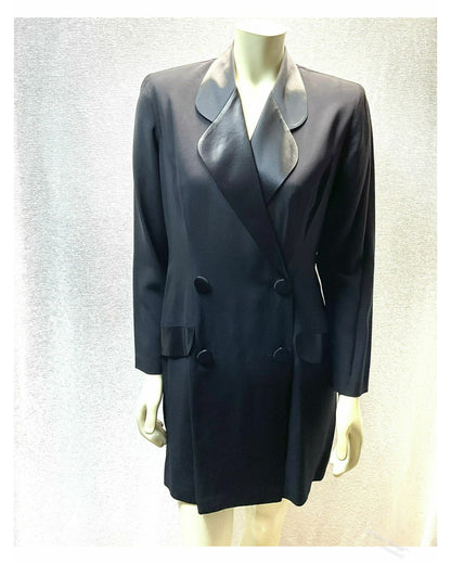 A black double-breasted tuxedo Style front Skort Romper with black satin lapels, displayed on a mannequin against a textured light white background.