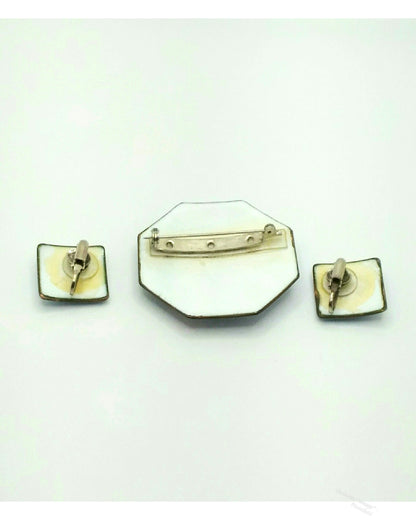 A vintage jewelry set featuring an octagonal enamel pin with a barrette clasp, flanked by two square enamel clip-on earrings with gold-toned metal borders and backs, displayed on a plain white background.