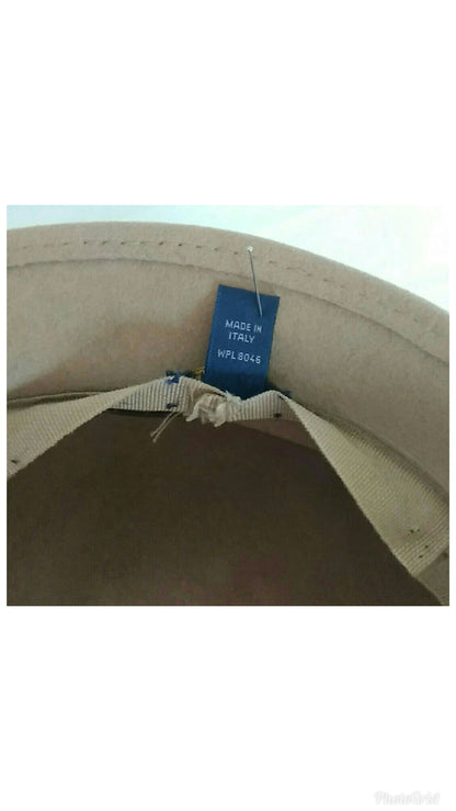 Close-up of the inside of a beige hat, showing a blue 'MADE IN ITALY' hangtag attached to a fabric loop.
