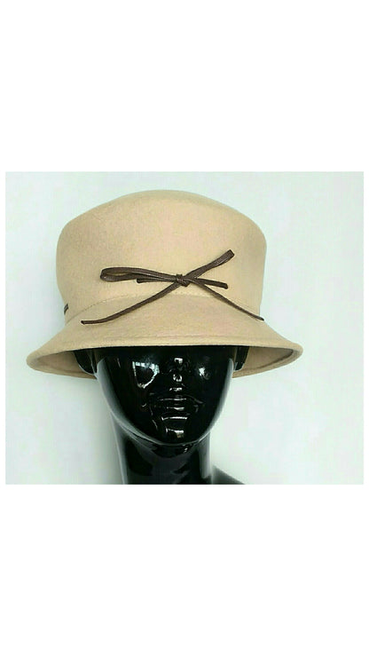 Front view of  Camel colored felt cloche hat with a brown bow detail, displayed on a black mannequin head against a white background.