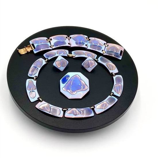 Video of  4 piece including a necklace, bracelet, matching earrings and brooch. The color palette is exceptional: a striking opalescent blue enamel with beautiful hints of lavender and purple tones faceted blue and white stones set in silver-toned metal