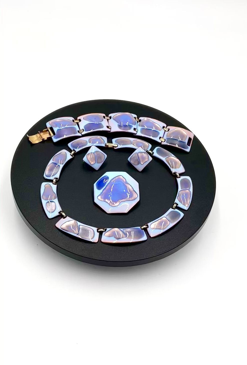 Video of  4 piece including a necklace, bracelet, matching earrings and brooch. The color palette is exceptional: a striking opalescent blue enamel with beautiful hints of lavender and purple tones faceted blue and white stones set in silver-toned metal